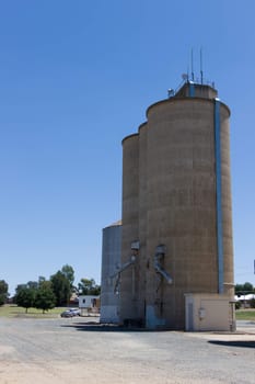 Large steel grain silos with cloudless blue skies.