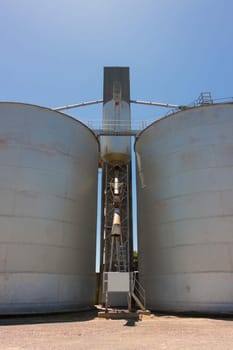 Large steel grain silos with cloudless blue skies.