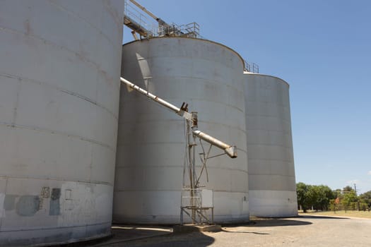 Large steel grain silos with cloudless blue skies.