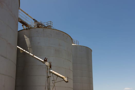 Large steel grain silos with cloudless blue skies.