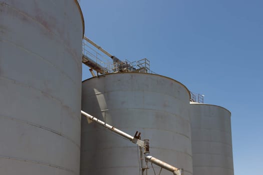 Large steel grain silos with cloudless blue skies.