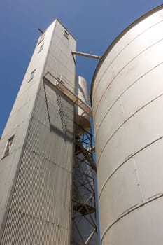 Large steel grain silos with cloudless blue skies.