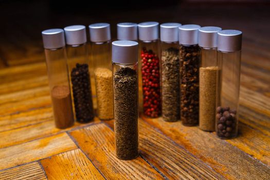 Assorted ground spices in bottles on wooden background