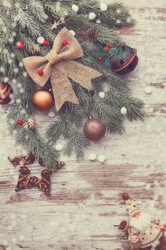 The tip of a tree branch and Christmas decoration on a rustic wood background.Top view,  blank space, vintage toned image