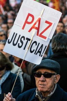 SPAIN, Madrid: A man holds a sign that reads 'Paz Justica' as thousands of people take to the streets of Spain's capital to protest Western military intervention on November 28, 2015.  The protesters gathered at Reina Sofia Museum and were joined by actor and anti-war activist Alberto San Juan.    	