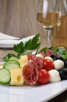 Appetizer of salami with mozzarella, olives, cherry tomatoes, cucumber and cheese on a skewer