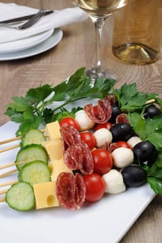 Appetizer of salami with mozzarella, olives, cherry tomatoes, cucumber and cheese on a skewer