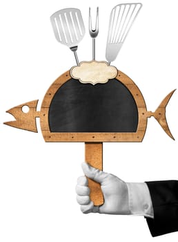 Chef holding a blackboard in the shape of fish and serving dome with kitchen utensils and empty label. Isolated on white background