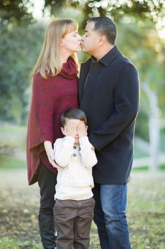 Loving Mix Race Couple Kissing As Young Son Hides His Eyes.