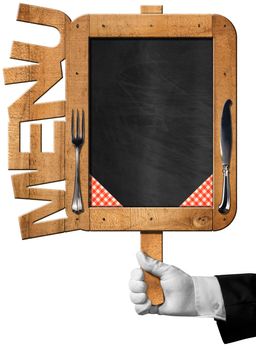 Hand of chef with white glove holding an old empty blackboard with wooden frame with text menu, silver cutlery and checkered tablecloth