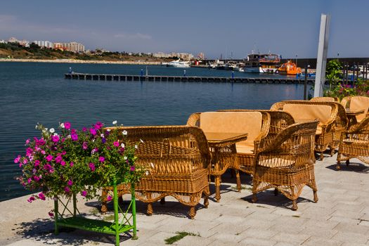 Rattan tables, chairs and benches at a terrace in Tomis harbor in Constanta Romania at the Black Sea