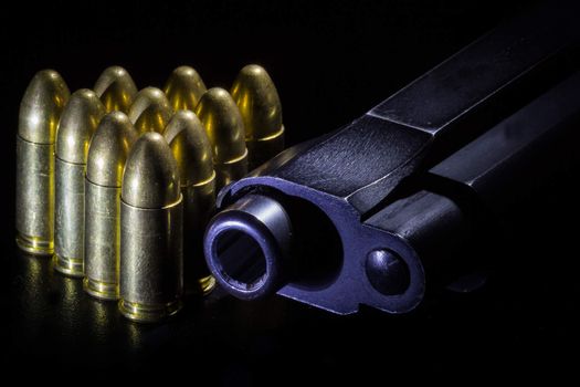 Black gun and bullets on a black background.