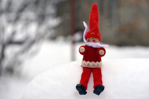 Red wooden doll in the snow with winter background