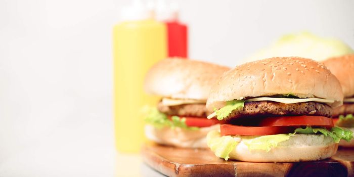 Hamburgers with cheese, potato chips and ingredients on a white background