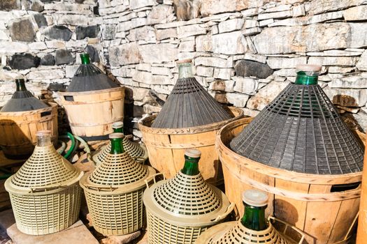 Demijohns of wine in a stone cellar.