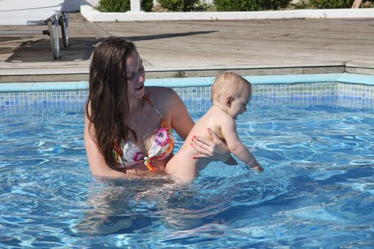 Mother teaching swimming her baby girl in the pool