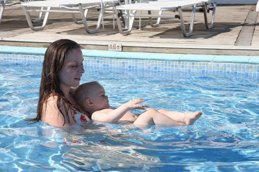 Mother teaching swimming her baby girl in the pool
