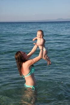 Mother playing with  her baby daughter  in the sea water