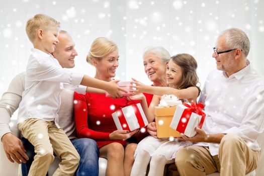 family, holidays, generation, christmas and people concept - smiling family with gift boxes sitting on couch at home