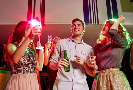 party, holidays, celebration, nightlife and people concept - smiling friends clinking glasses of champagne and beer in club