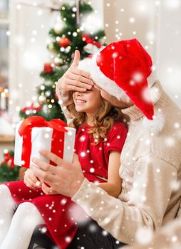 christmas, holidays, family and people concept - smiling father and daughter in santa hats holding gift box and covering eyes at home