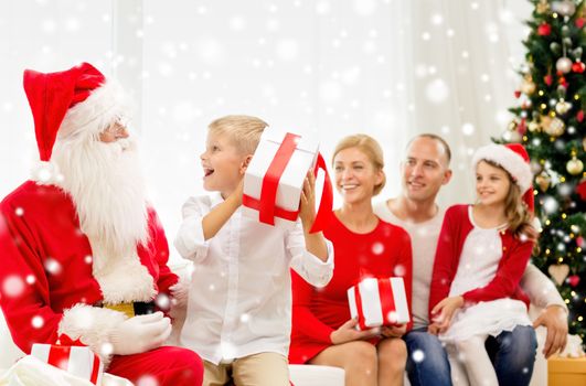 family, holidays, generation, christmas and people concept - smiling family with santa claus and gift boxes at home