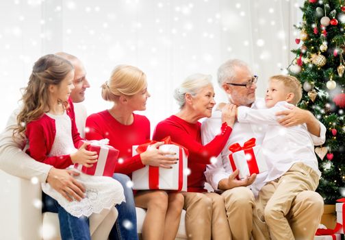 family, holidays, generation, christmas and people concept - smiling family with gift boxes sitting on couch at home