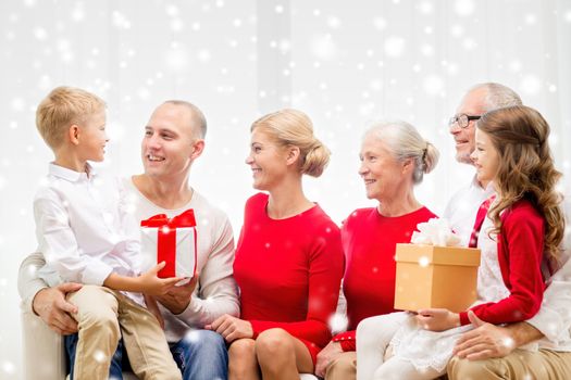 family, holidays, generation, christmas and people concept - smiling family with gift boxes sitting on couch at home