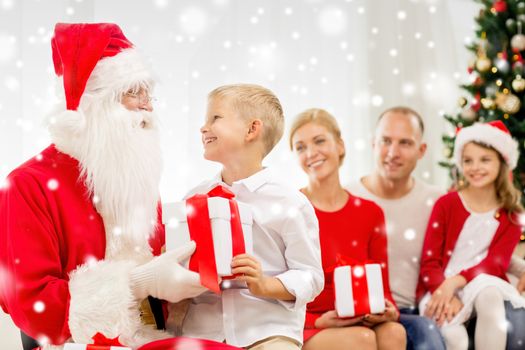 family, holidays, generation, christmas and people concept - smiling family with santa claus and gift boxes at home