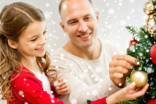 family, holidays, generation and people concept - smiling girl with father decorating christmas tree at home