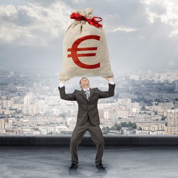 Businessman holding big moneybag with euro sign with city view
