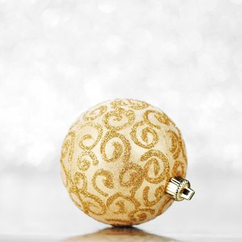 Beautiful golden christmas ball on abstract glitter background close-up