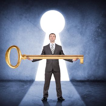 Businessman in suit holding huge gold key