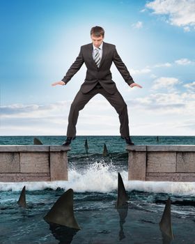 Businessman in suit standing above sharks in water