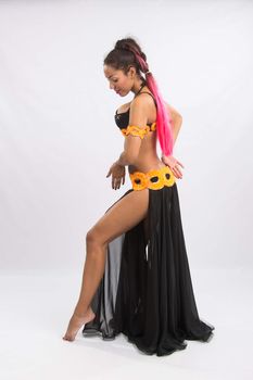 Young girl mulatto dancing in a long black candid open dress, is isolated on a light background