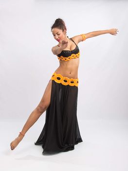 Young girl mulatto dancing in a long black candid open dress, is isolated on a light background