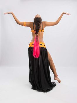 Young girl mulatto dancing in a long black candid open dress, is isolated on a light background