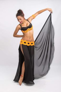 Young girl mulatto dancing in a long black candid open dress, is isolated on a light background