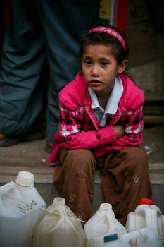 NEPAL, Patan: A Nepalese girl waits with empty gas tanks in Patan, Nepal on November 29, 2015 as fuel supplies dwindle. Blockades of major trade routes with India have continued after months of unrest over the nation's new constitution, opposing the demarcation of communities, and a perceived lack of representation in the constitution.
