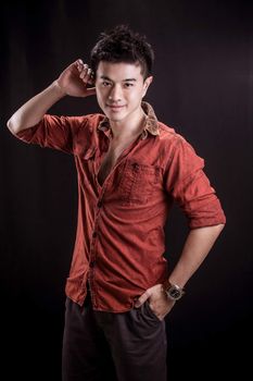 Portrait of Asian young man on black background - casual red shirt