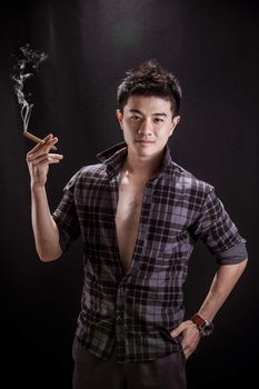 Portrait of Asian young man on black background - handsome young man hold cigar