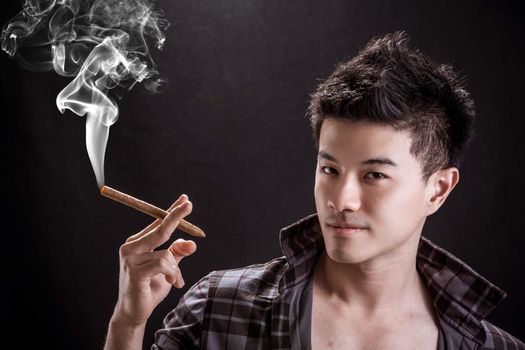 Portrait of Asian young man on black background - handsome young man hold cigar