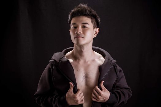 Portrait of Asian young man on black background - Fitness healthy guy thumb up