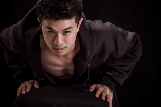 Portrait of Asian young man on black background - Fitness healthy guy pushing up