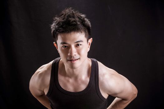 Portrait of Asian young man on black background - Show muscle and strengh