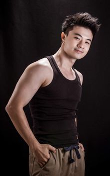 Portrait of Asian young man on black background - Show muscle and strengh