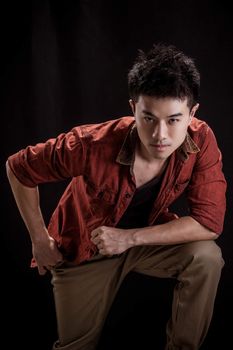 Portrait of Asian young man on black background - Casual red shirt and posing