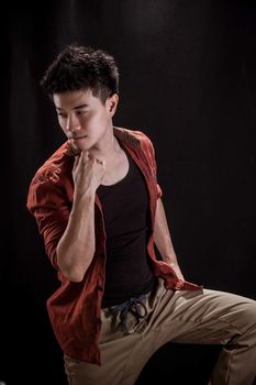 Portrait of Asian young man on black background - Casual red shirt and posing