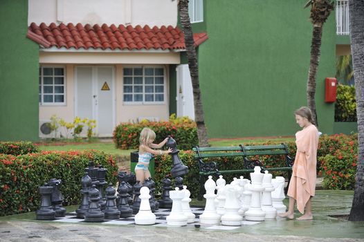 Girls in towels are playing chess with big figures.