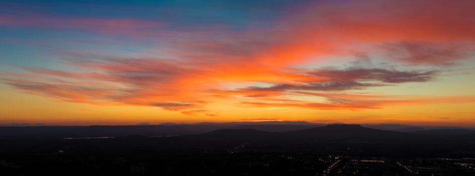 panoramic view of sunset scene with mountains in background, colorful sky with soft clouds